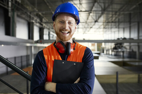 Porträt eines glücklichen Arbeiters in einem Fabriklager, lizenzfreies Stockfoto