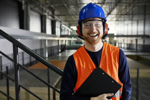 Porträt eines glücklichen Arbeiters in einem Fabriklager, lizenzfreies Stockfoto