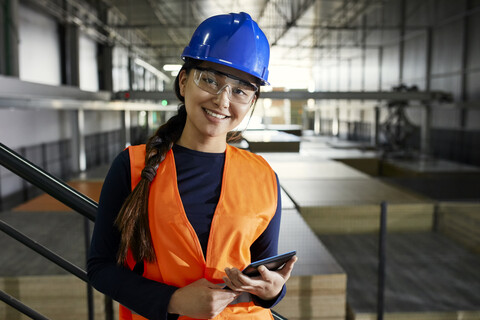 Porträt einer selbstbewussten Arbeiterin in einem Fabriklager, lizenzfreies Stockfoto