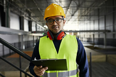 Portrait of worker holding clipboard in factory warehouse - ZEDF02253