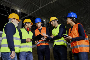 Arbeiter stehen in einem Fabriklager und unterhalten sich - ZEDF02256