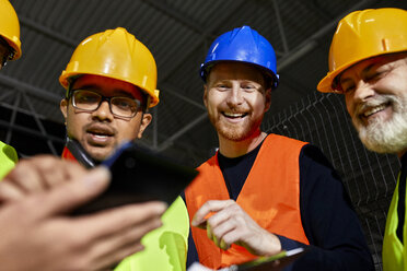 Happy workers in factory warehouse talking and using tablet - ZEDF02259