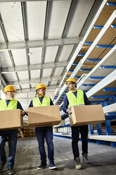 Three workers carrying boxes in factory warehouse - ZEDF02265