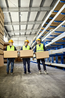 Drei Arbeiter tragen Kisten in einem Fabriklager - ZEDF02266