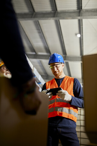 Arbeiter im Fabriklager mit Tablet, lizenzfreies Stockfoto
