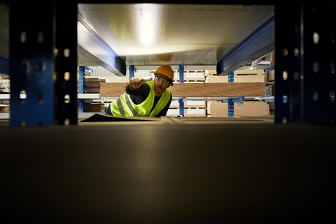 Arbeiter mit Taschenlampe sucht etwas in einem Fabriklager, lizenzfreies Stockfoto