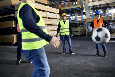 Workers playing football in factory warehouse stock photo