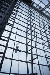 Low angle view of window washer hanging outside building - BLEF00011