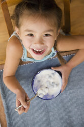 Gemischtrassiges junges Mädchen isst Joghurt mit Löffel - BLEF00058