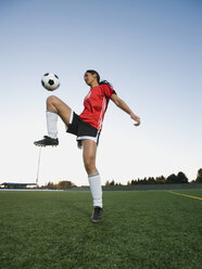 Mixed race woman bouncing soccer ball on knee - BLEF00068