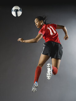 Mixed race soccer player in air with soccer ball - BLEF00073