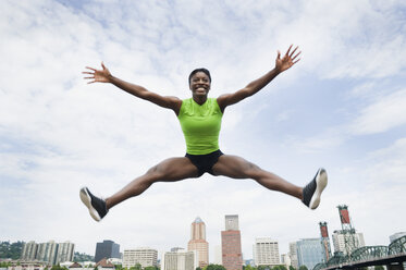 Afrikanische Frau springt mit Stadt im Hintergrund - BLEF00080