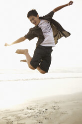 Mixed race boy jumping on beach - BLEF00088