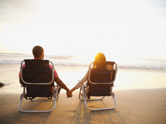 Couple holding hands on beach at sunset - BLEF00100
