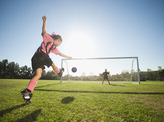 Girl soccer player kicking soccer ball at net - BLEF00108
