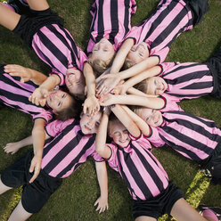 Girl soccer players laying in circle with arms raised - BLEF00111