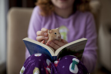 Kaukasisches Mädchen sitzt mit Buch und Hamster - BLEF00116