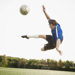 Caucasian soccer player in mid-air kicking soccer ball - BLEF00124