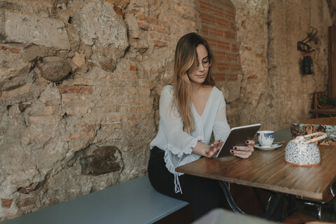 Junge Frau benutzt Tablet in einem Café, lizenzfreies Stockfoto