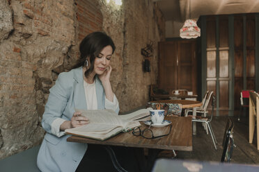 Junge Frau liest ein Buch in einem Café - AHSF00126