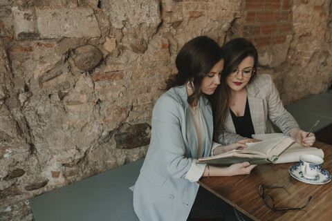 Two young women with notebook and book in a cafe stock photo