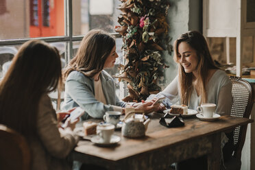 Drei glückliche junge Frauen mit Handy treffen sich in einem Cafe - AHSF00130