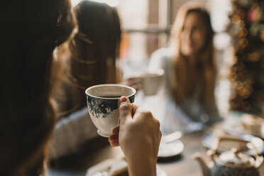 Nahaufnahme einer Frau mit Freunden in einem Café, die eine Tasse halten - AHSF00136