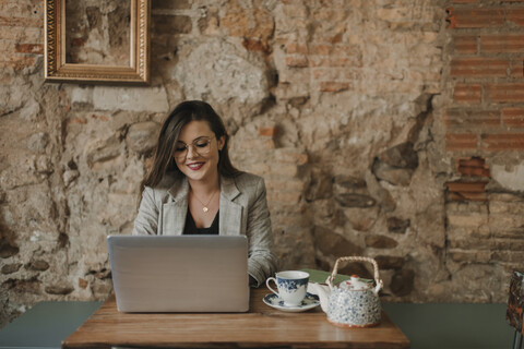 Lächelnde junge Frau mit Laptop in einem Cafe, lizenzfreies Stockfoto