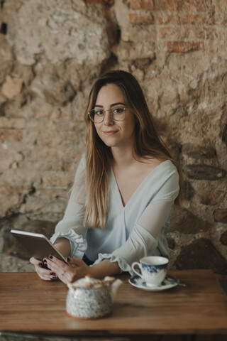 Porträt einer jungen Frau, die in einem Café ein Tablet benutzt, lizenzfreies Stockfoto
