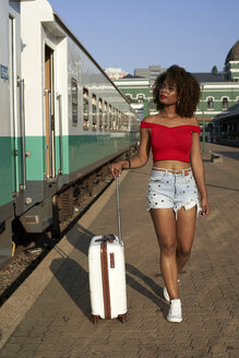 Frau geht mit ihrem Koffer am Bahnhof spazieren - VEGF00049