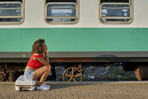 Frau mit Koffer auf dem Bahnhof sitzend - VEGF00061