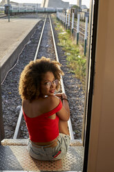 Woman sitting at the back door of a train turning round - VEGF00065