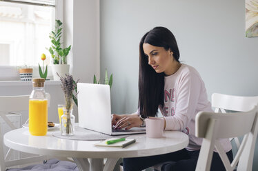 Beautiful young woman typing on a laptop keyboard at home - MOMF00697