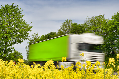 Truck in motion behind rape field stock photo