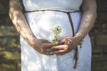 Pregnant woman holding flowers, close up - ASCF00997