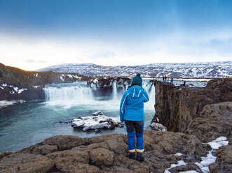 Iceland, woman at Godafoss Waterfall in winter - TAMF01302