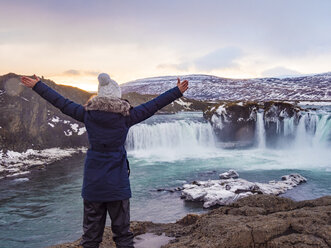 Island, Frau am Godafoss-Wasserfall im Winter - TAMF01303