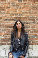 Portrait of young woman wearing black leather jacket, brick wall - MGIF00394