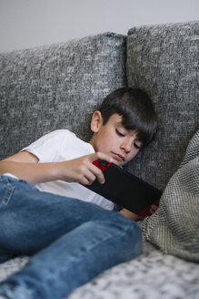 Junge liegt auf der Couch und spielt ein Computerspiel - JCMF00040