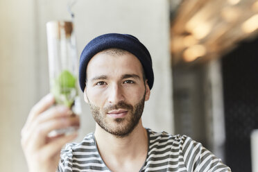 Porträt eines jungen Mannes, der eine Pflanze in einem Gefäß hält - FMKF05614