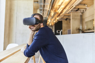 Young man wearing VR glasses in modern office - FMKF05625