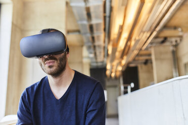 Young man wearing VR glasses in modern office - FMKF05626