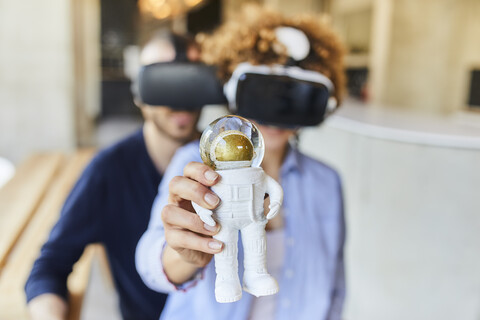 Man and woman wearing VR glasses holding astronaut figurine stock photo