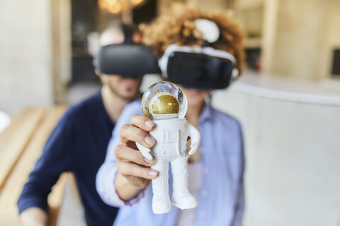 Mann und Frau mit VR-Brille halten eine Astronautenfigur, lizenzfreies Stockfoto