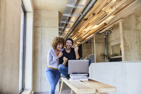 Excited man and woman with laptop in modern office stock photo
