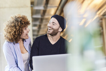 Excited man and woman with laptop in modern office - FMKF05635