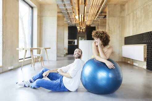 Smiling man and woman with fitness ball in modern office - FMKF05652
