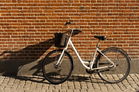 Dänemark, Kopenhagen, Fahrrad gegen Backsteinmauer gelehnt im Sonnenlicht, lizenzfreies Stockfoto