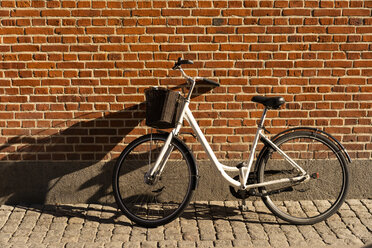Dänemark, Kopenhagen, Fahrrad gegen Backsteinmauer gelehnt im Sonnenlicht - AFVF02729