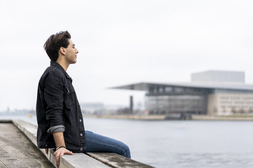 Dänemark, Kopenhagen, junger Mann sitzt am Wasser - AFVF02741
